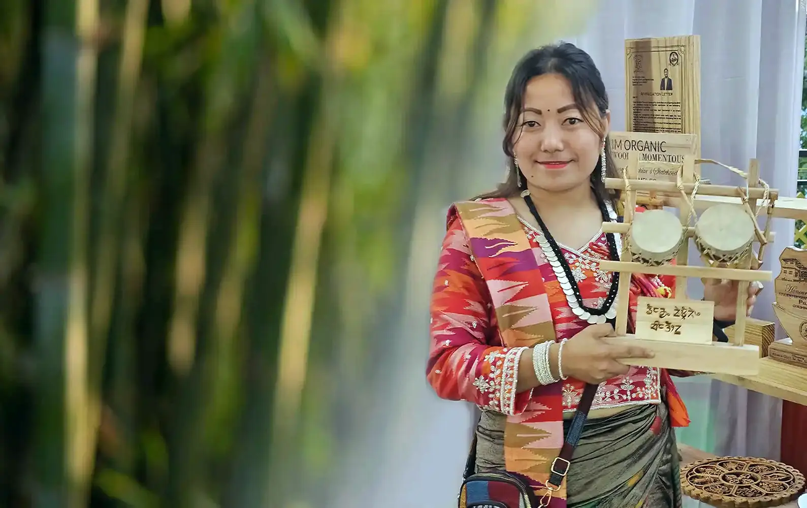 Woman in traditional Sikkimese attire holding handcrafted bamboo souvenirs made by Khechuperi Bamboo House