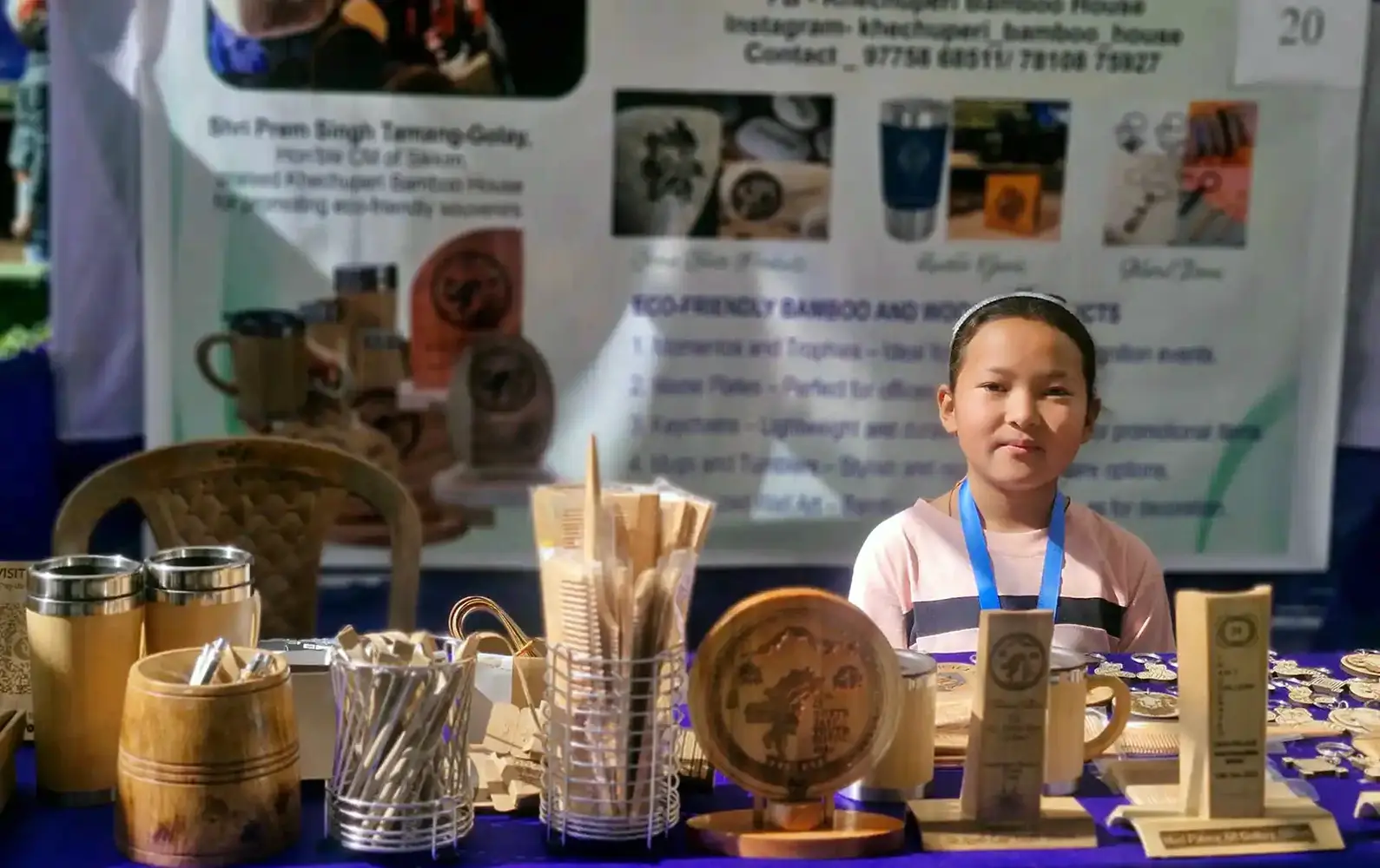 Young artisan sitting at the stall of Khechuperi Bamboo House showcasing handmade bamboo and wooden souvenirs.